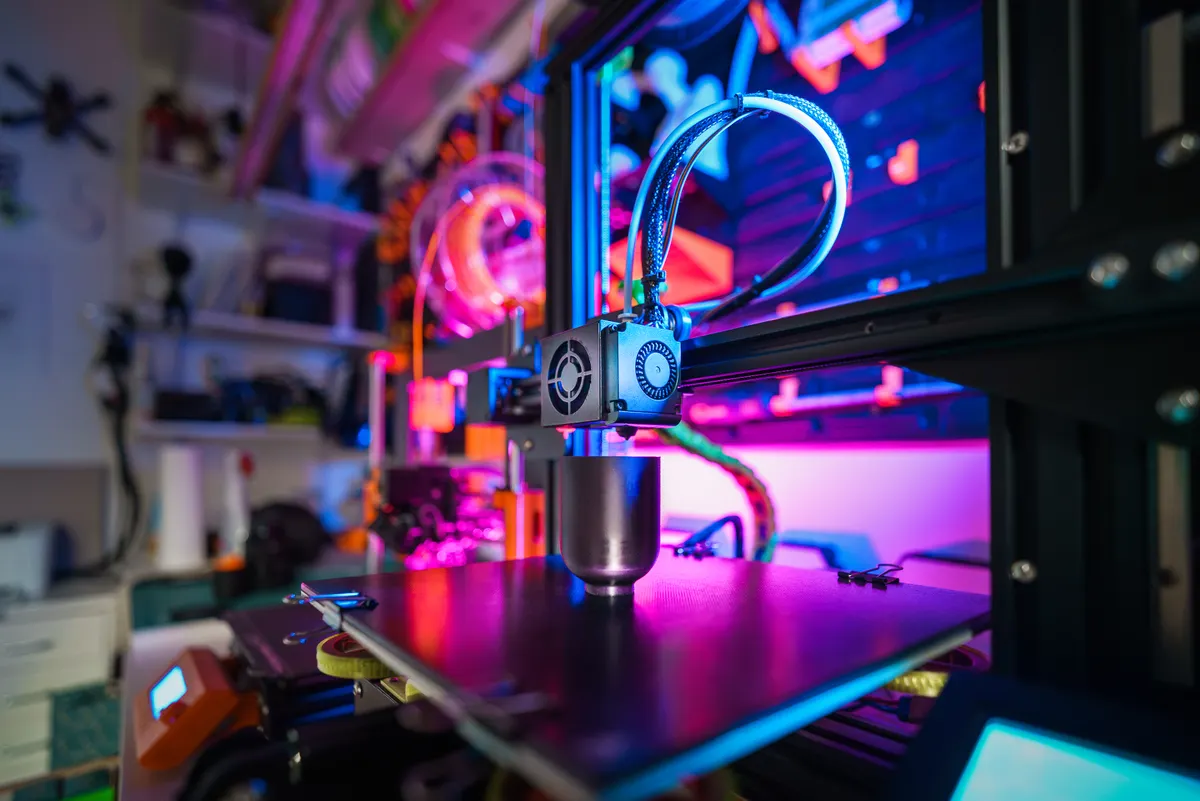3D-Drucker mit Kamera-Überwachung in einer bunt beleuchteten Werkstatt
