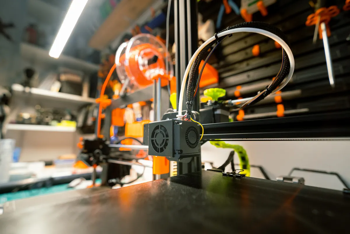3D-Drucker mit oranger Filamentrolle in einer Werkstatt