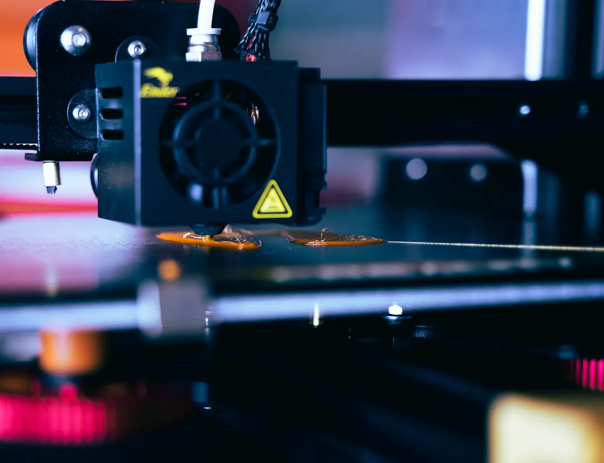 Düse eines 3D-Druckers über einer misslungenen ersten Schicht mit Materialklumpen